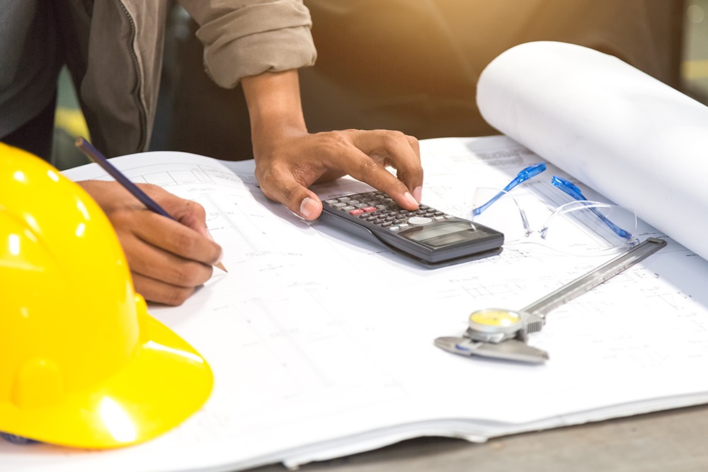 Expert construction estimator using a calculator and measuring tools to provide accurate material takeoff and cost estimation.